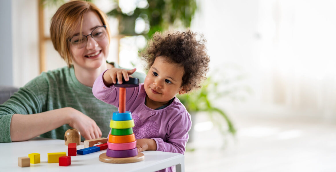 Mother looking at a child playing with an educational didactic toy