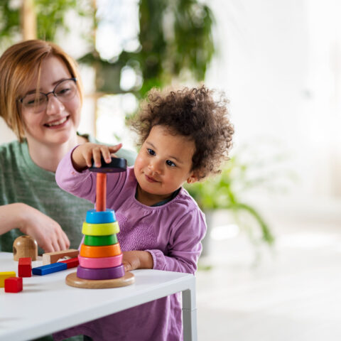 Mother looking at a child playing with an educational didactic toy