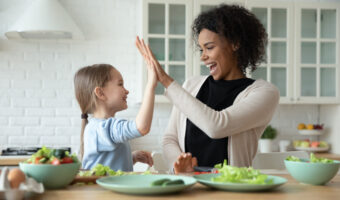 Happy multiethnic mom and little daughter have fun cooking