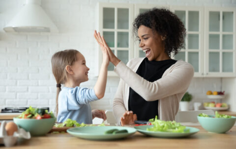 Happy multiethnic mom and little daughter have fun cooking