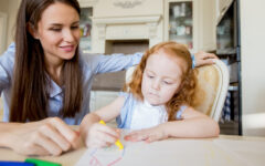 Happy mother or nanny looking at drawing girl